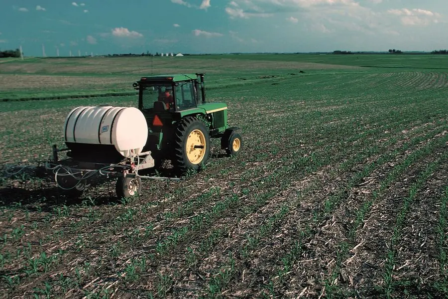 Soil application of fertilizer, tractor applying fertilizer to a young crop field as top dressing
