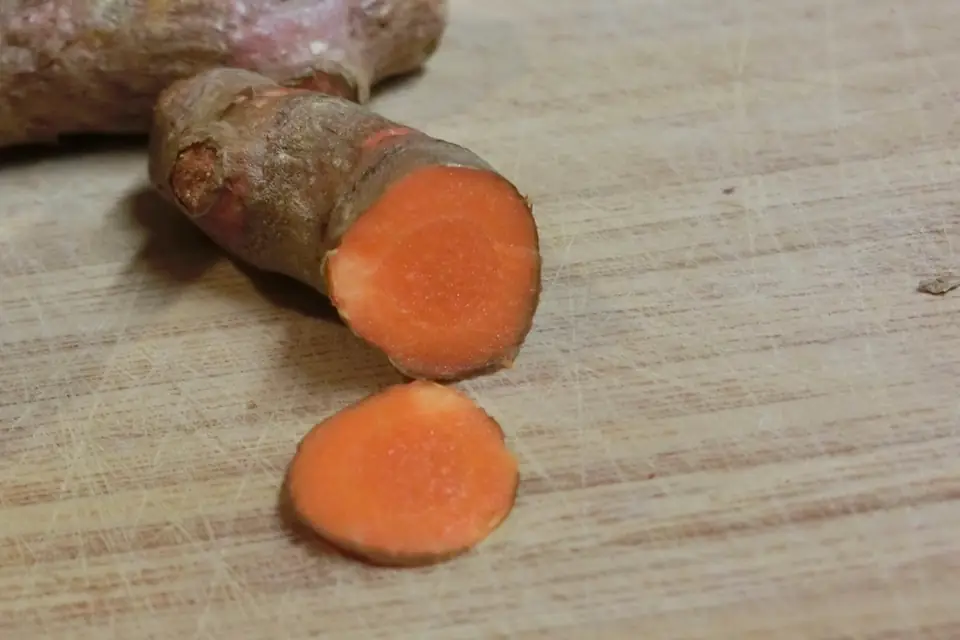 Fresh turmeric rhizome cut to show its orange interior